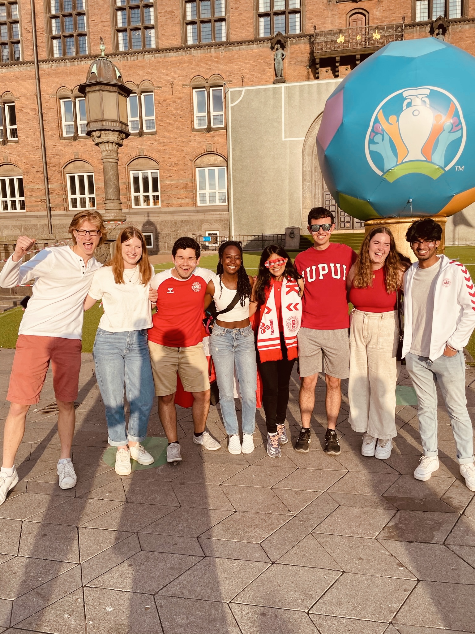 A group of students celebrate in front of a historic building and a giant inflated Euro Cup ball